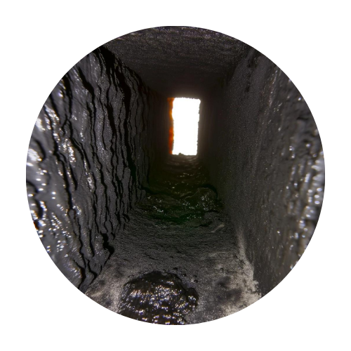 The inside view of a chimney flue showing a darkened interior with significant creosote buildup." "Another view inside a chimney flue, highlighting the textured creosote accumulation and narrow exit at the top.